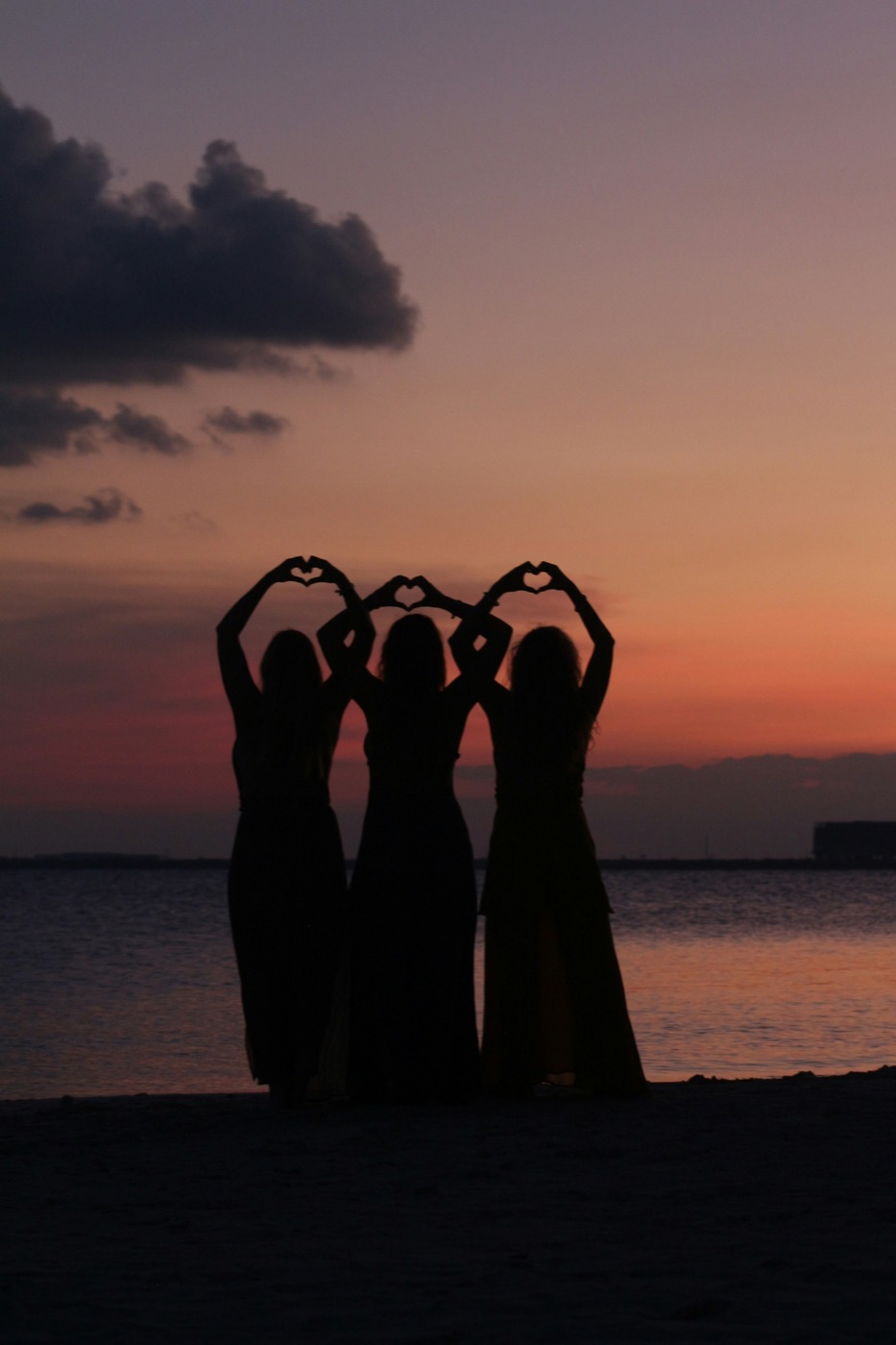 Friends making hearts at sunset